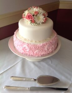 Two tier wedding cake with pink icing on bottom