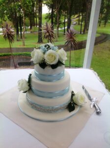 Three Tiered Wedding Cake with blue ribbon and white flowers