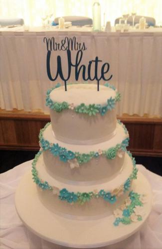 Fondant 3 tier sugar flower decorations in blue, green and white Wedding Cake.